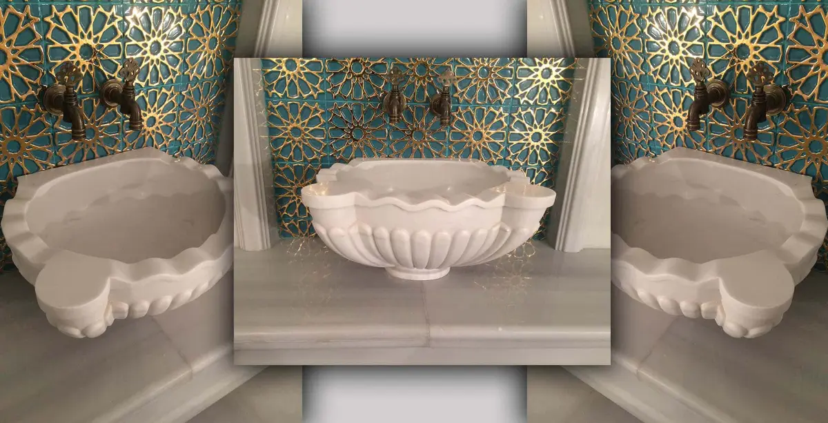 Fluted white marble basin with brass taps against turquoise tiles with raised gold geometric patterns