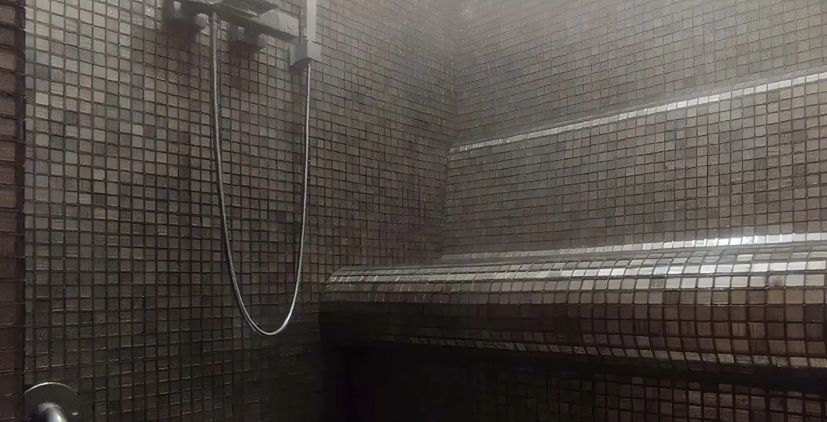 Steam-filled mosaic room with a curved bench, LED strips and a wall hand shower