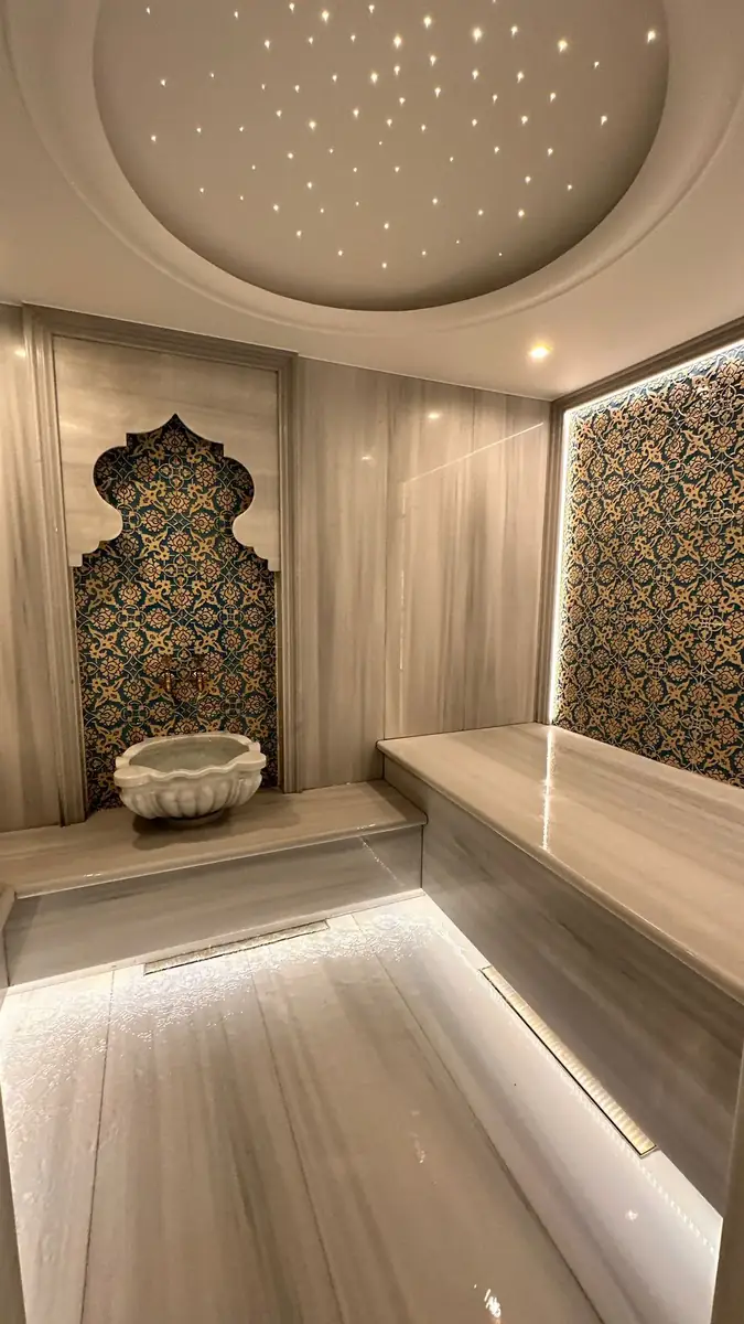Bodrum villa hammam with marble bench, kurna basin and backlit Iznik tile panel