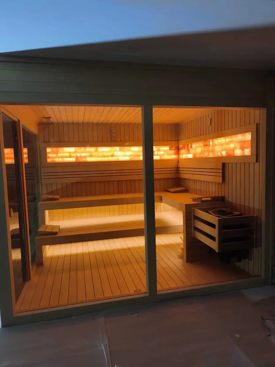 Sauna interior seen through two fixed glass panels with the hinged glass door standing open