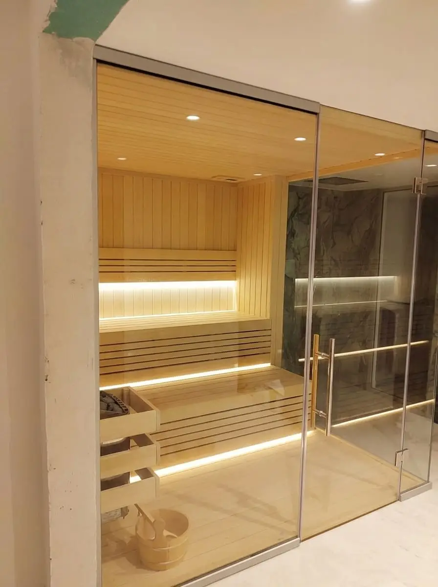 Ikoyi villa sauna installed against a dark marble wall, viewed from the wellness room