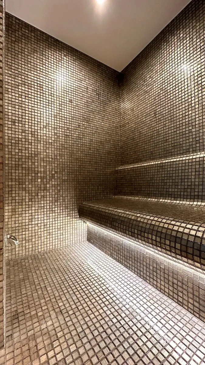 The Springs villa steam room with a contoured mosaic bench and concealed lighting