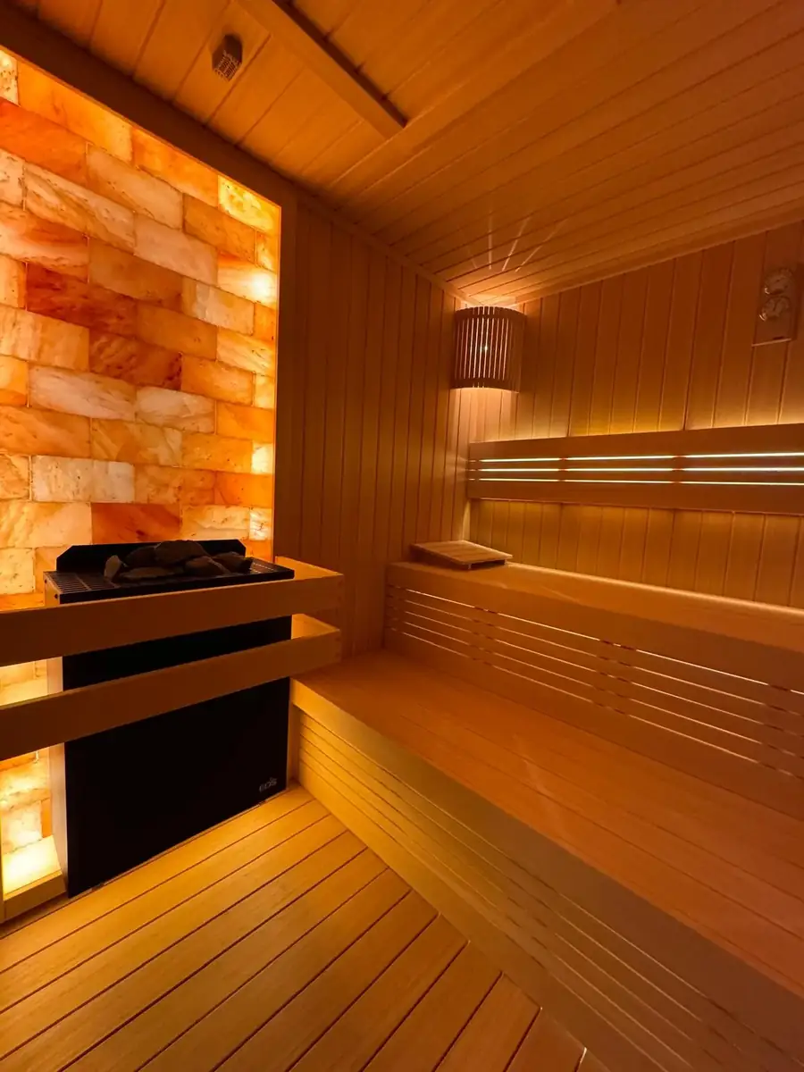 Private villa hybrid sauna with a backlit salt brick wall, stone heater and infrared panel